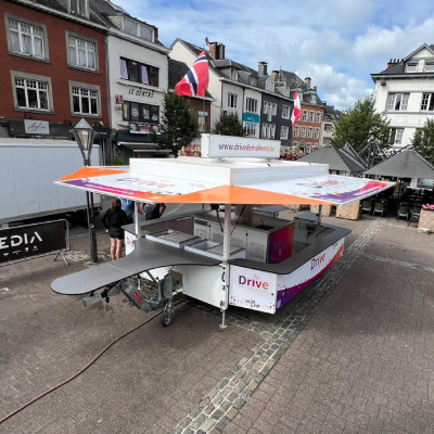 Photo montrant la buvette mobile du Drive de Malmedy déployée sur une place publique lors d'un festival de musique