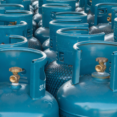 Rangée de bonbonnes de gaz propane en acier bleu, prêtes à l'utilisation, illustrant un stock de bonbonnes de gaz disponibles à la vente ou à la livraison.