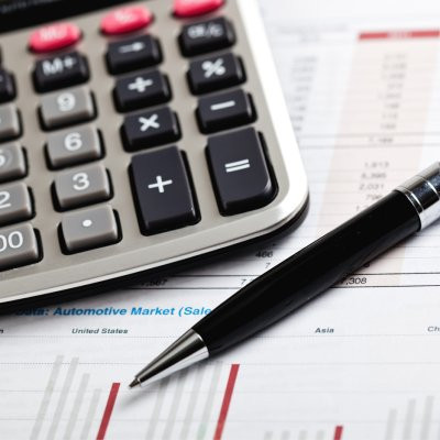 Photo montrant une calculatrice et un stylo posés sur un document avec des graphiques